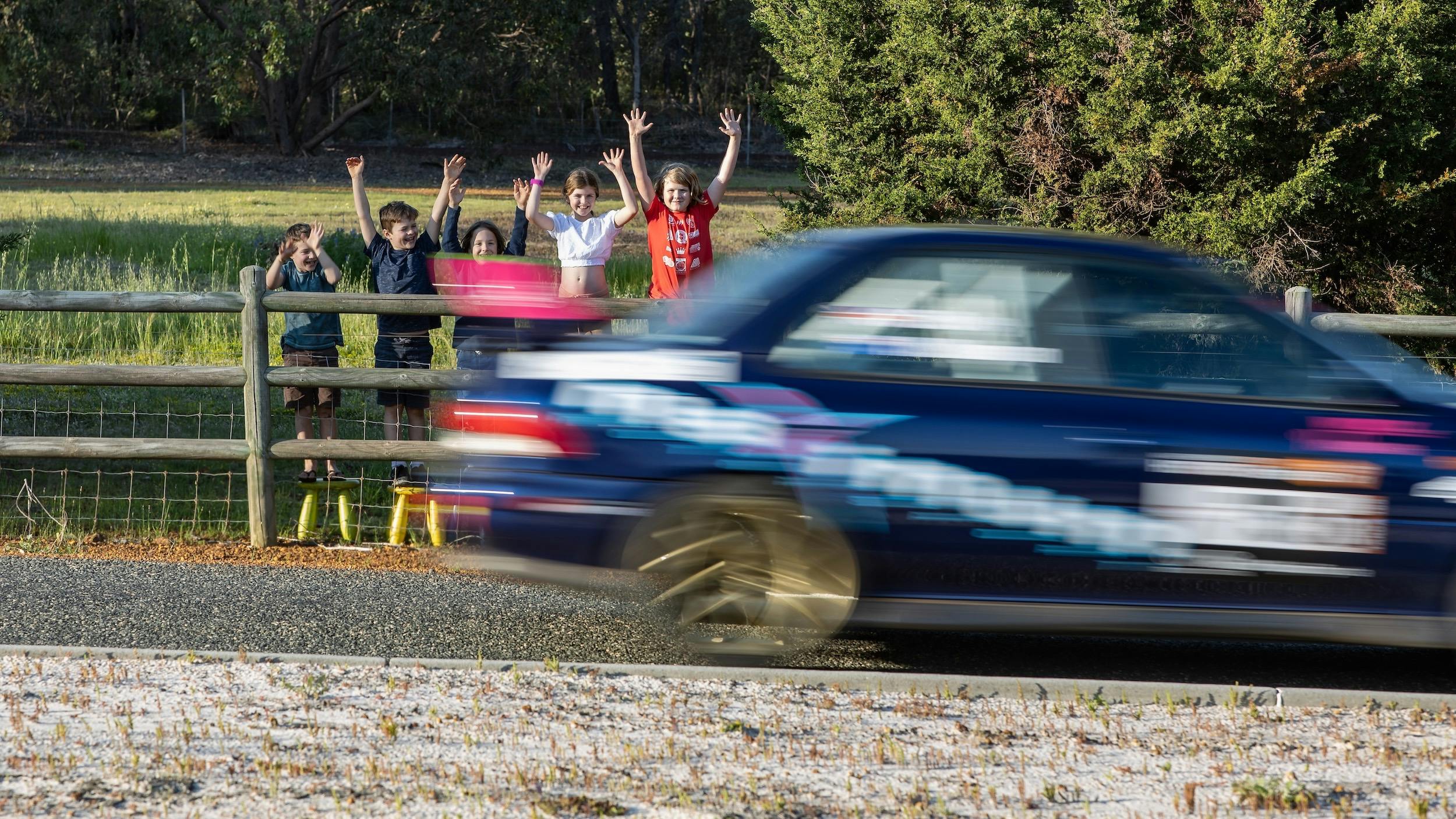 Rally car zooming past cheering kids in Toodyay