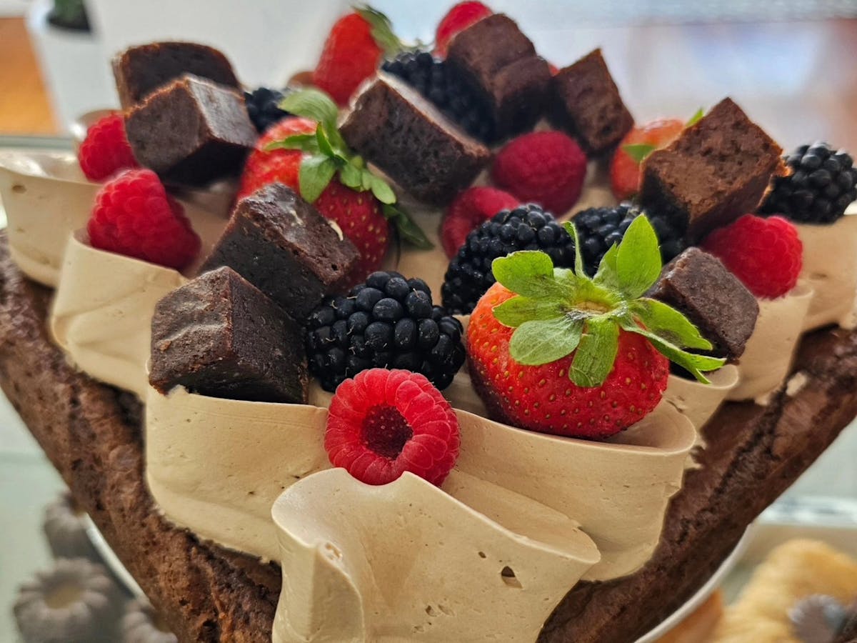 Brownie cake with icing brownie pieces and berries on top