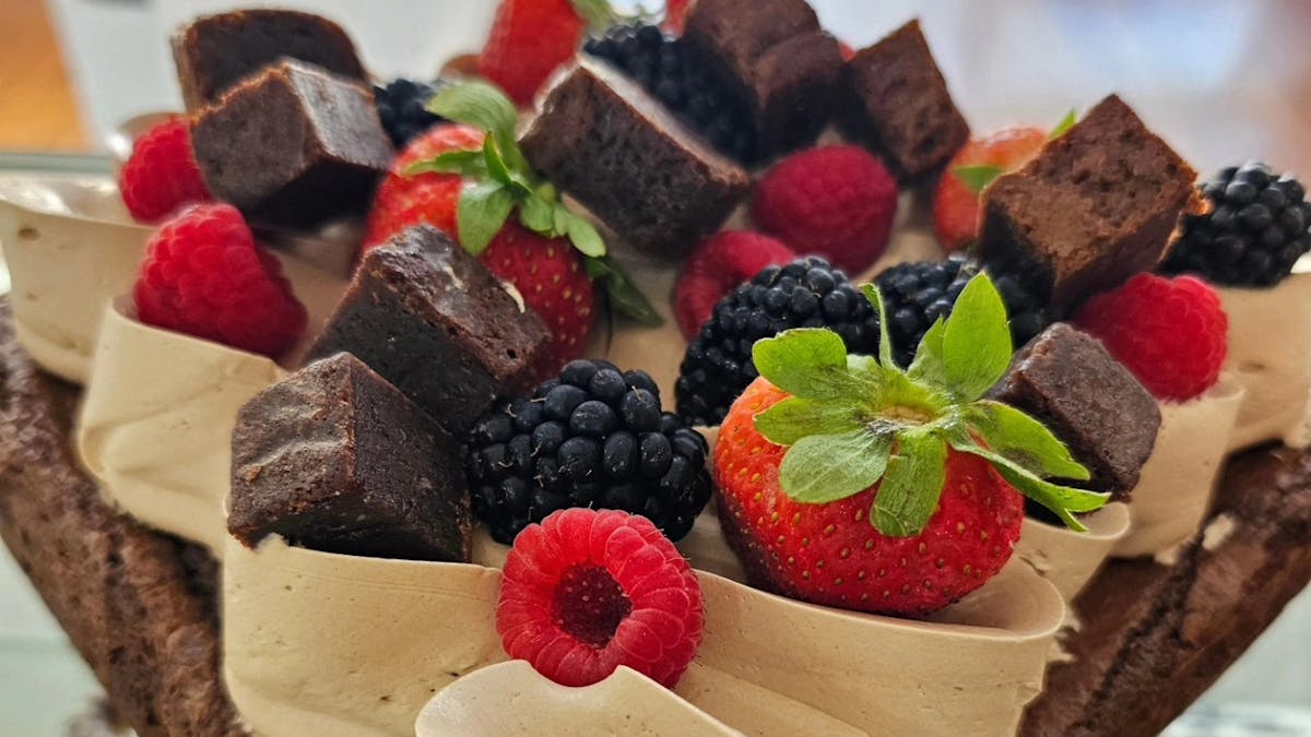 Brownie cake with icing brownie pieces and berries on top