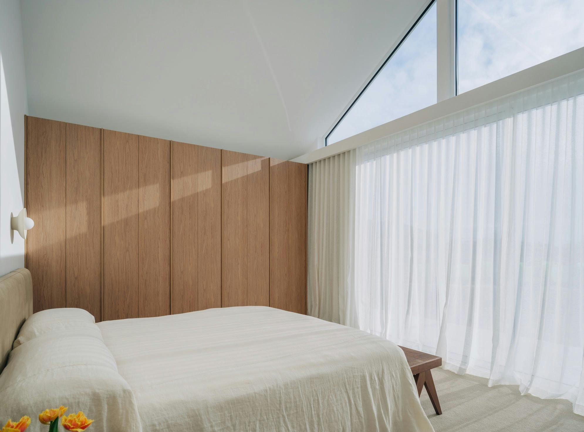 King size bed with bed head, bedside tables and nice linen bedding in large bedroom