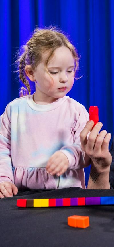 Two children and a man explore patterns using coloured blocks