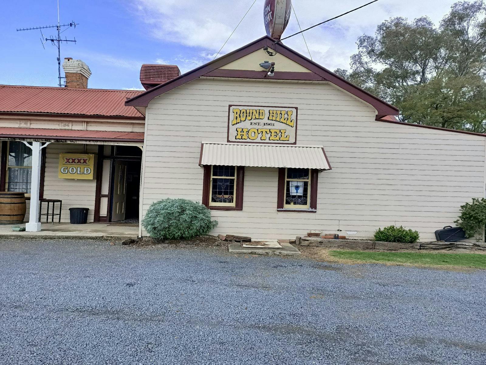 Out the front of the Roundhill Hotel, white building with yellow signing and brown accents.