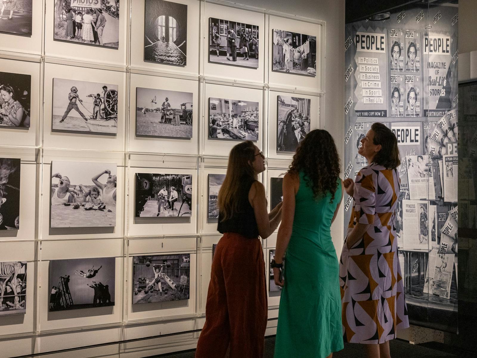 Three women talking in a photography exhibition
