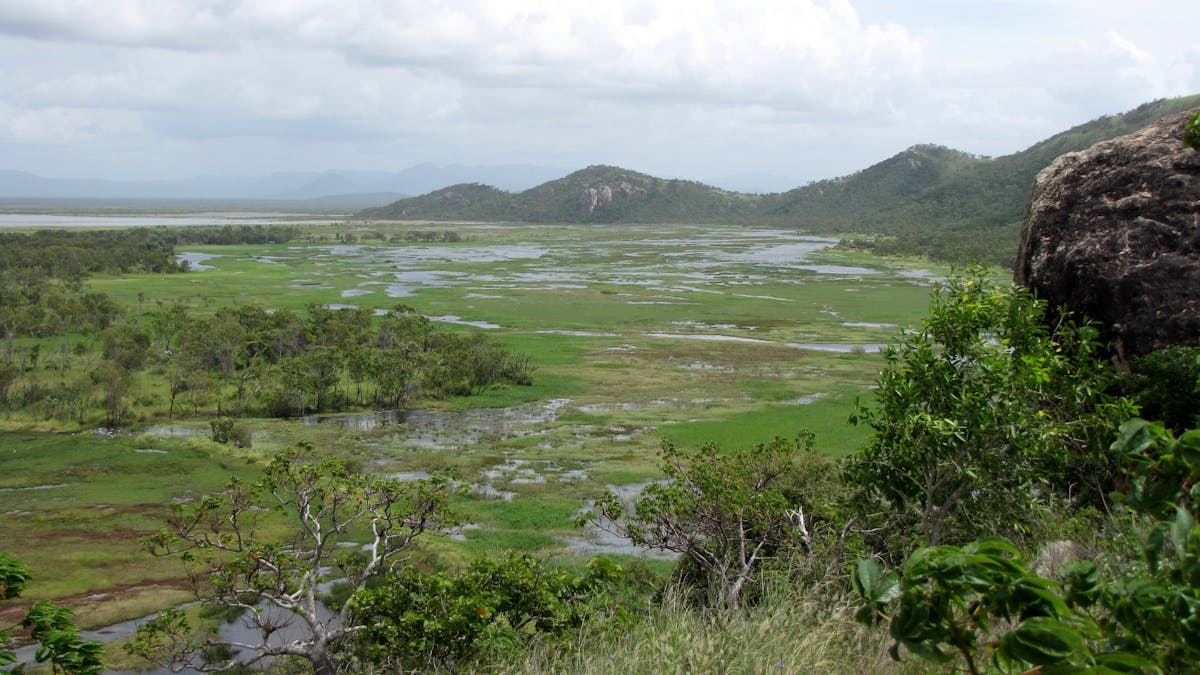 Views of coastal plain, distant mountains and ocean from high vantage point.