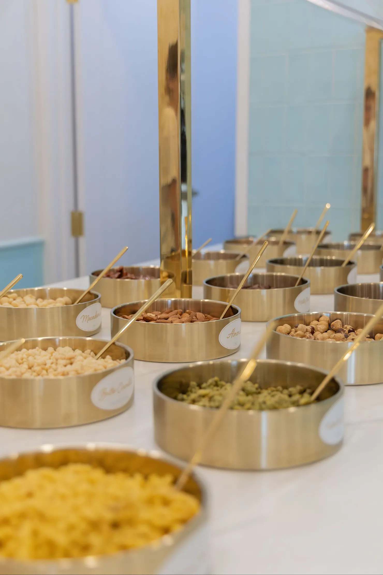 Gold bowls filled with toppings at the self-serve station inside LUMA Gelato
