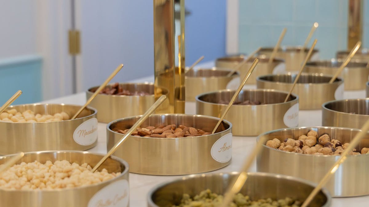 Gold bowls filled with toppings at the self-serve station inside LUMA Gelato