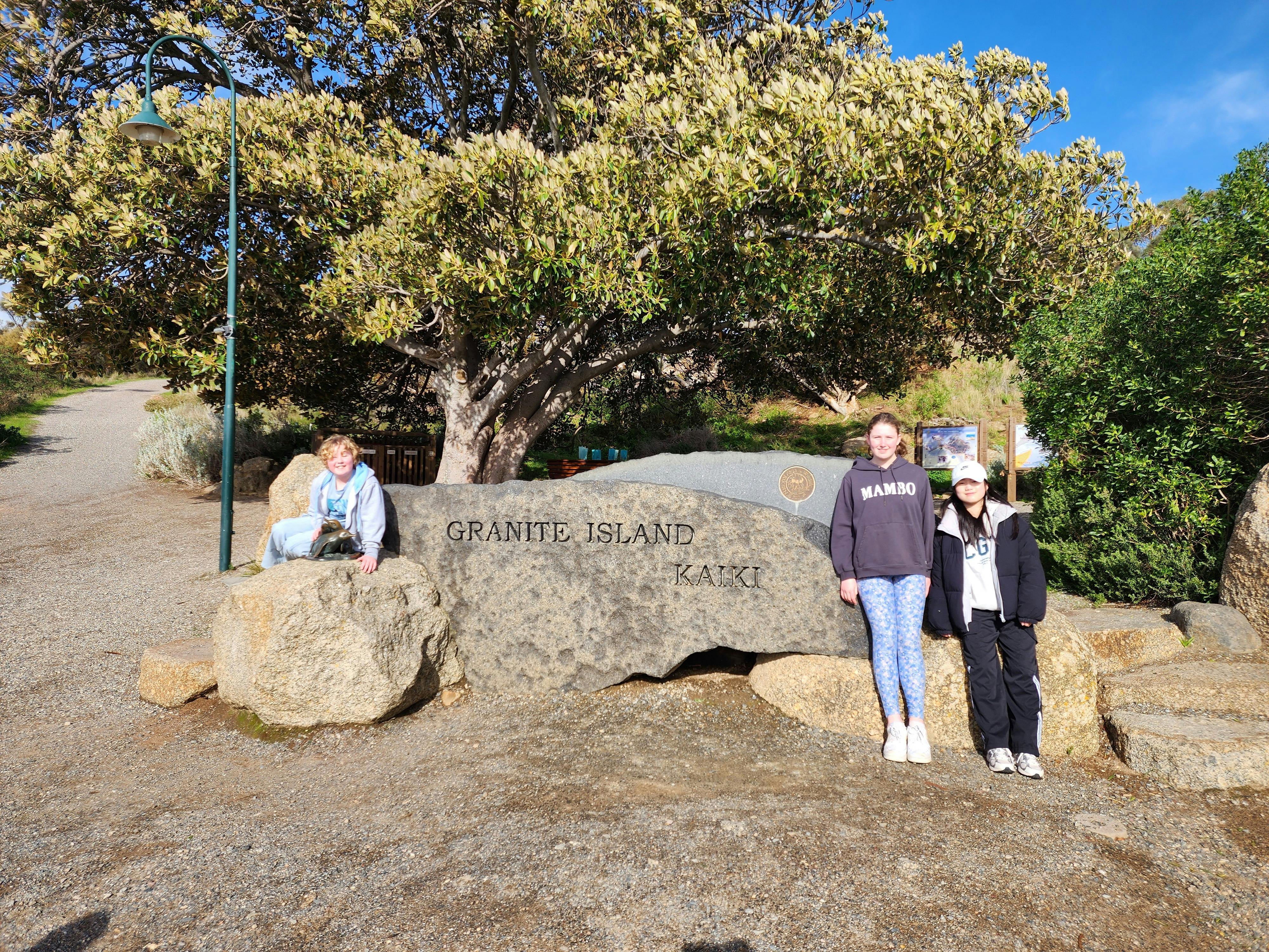 3 people posing at the Granite Island Entry Sign in Victor Harbor