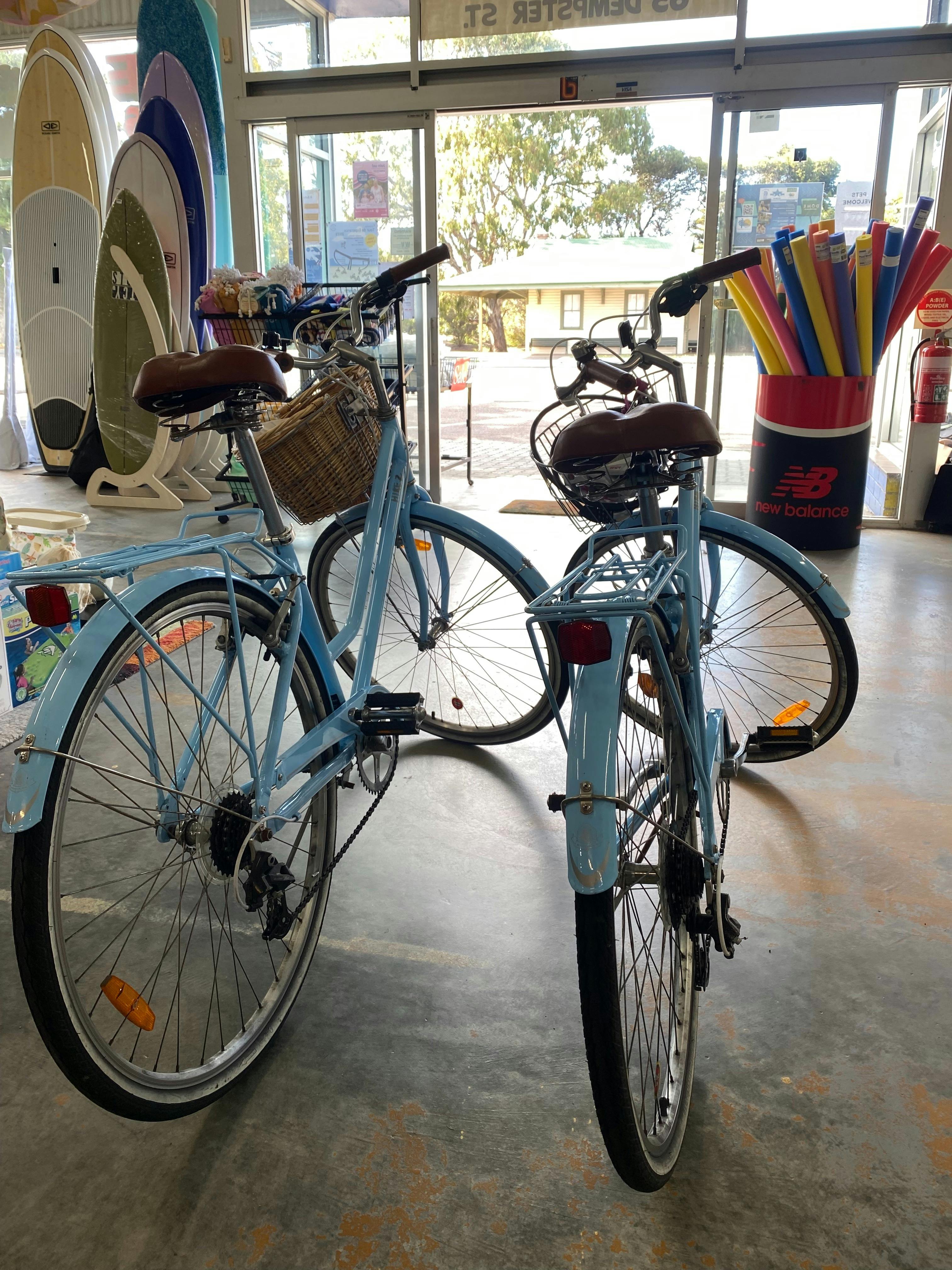 two blue cruiser style bicycles in a shop