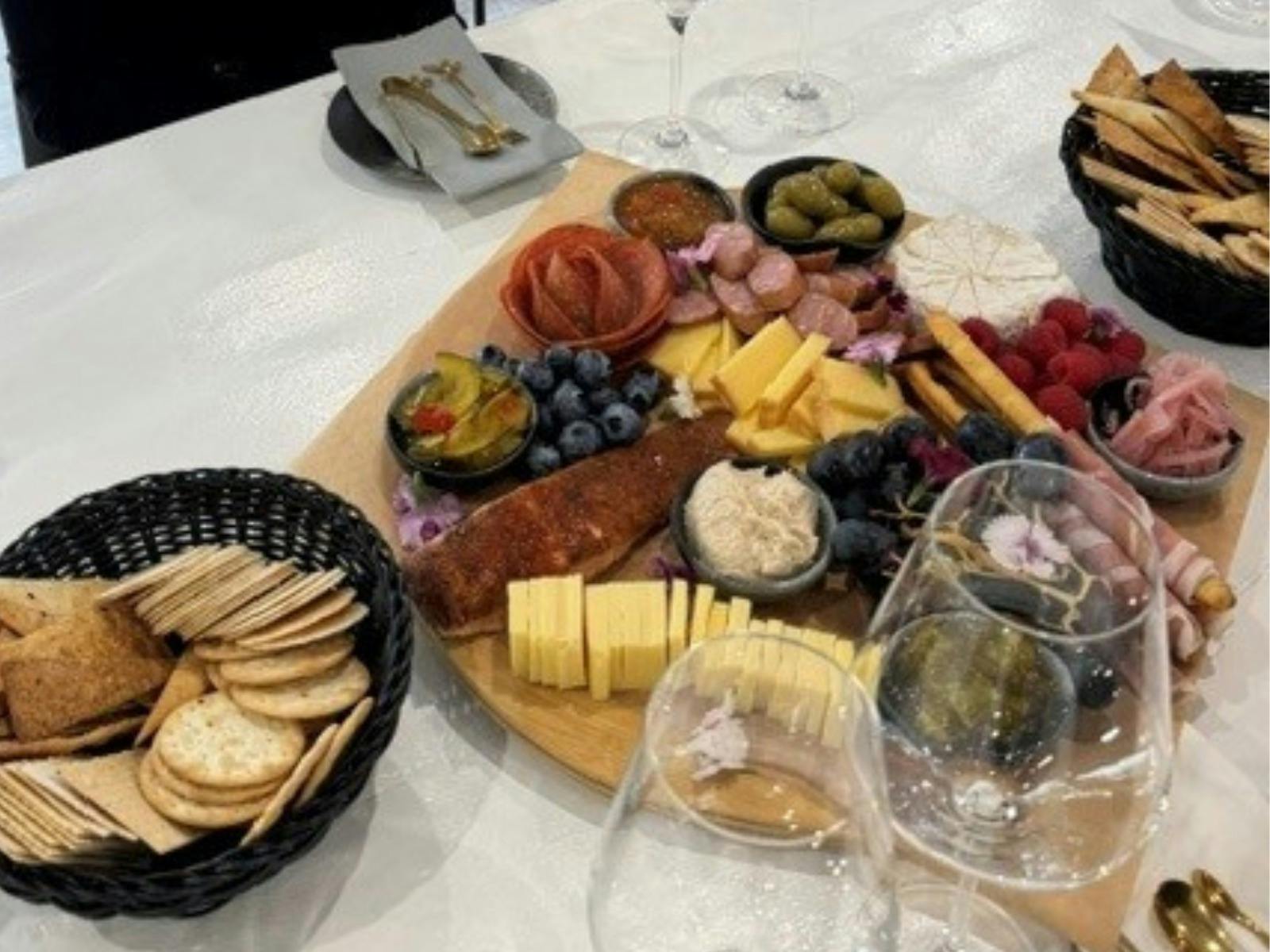 A charcuterie platter with glasses of wine on a table.