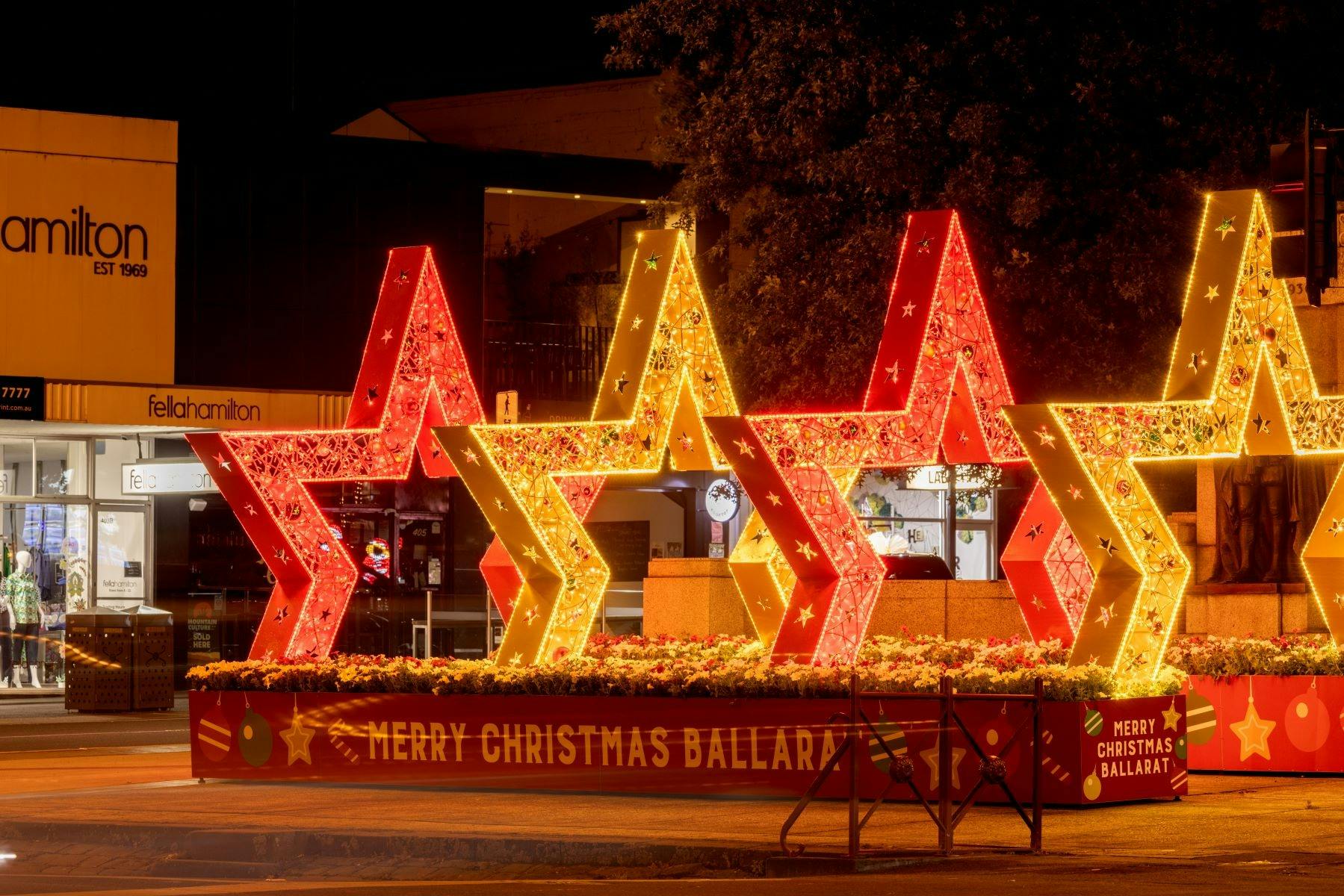 2 red and 2 gold stars create an archway, and are lit up with Christmas lights