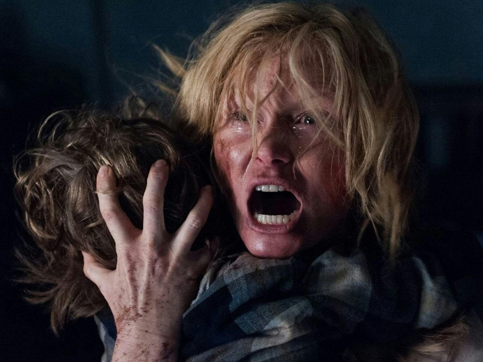 A woman with blonde hair is screaming while holding a child in their arms