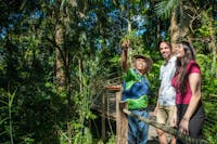 Lady and man standing in the rainforest next to a Ranger Guide pointing up