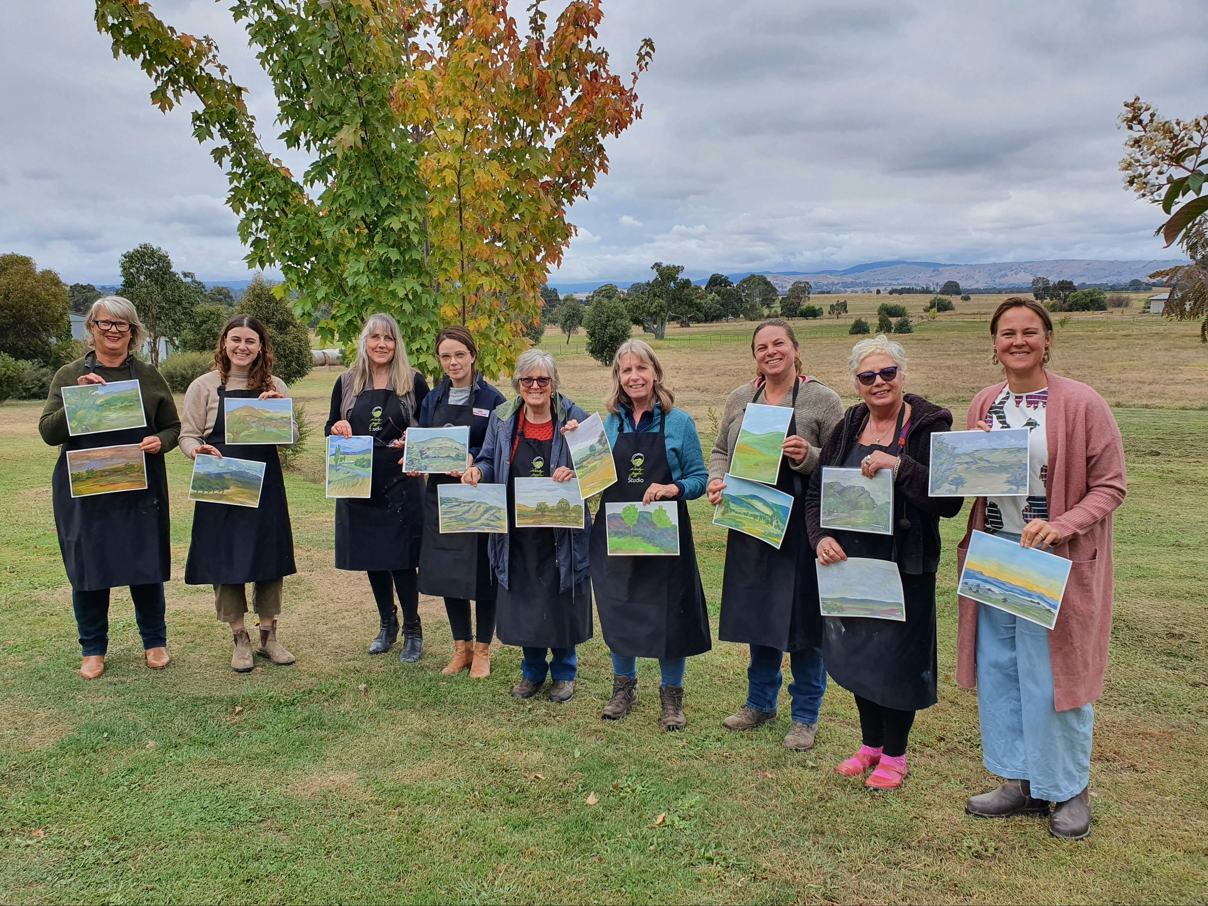 participants in painting workshop holding up their paintings