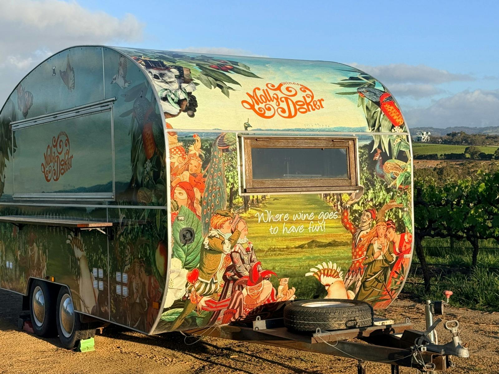 A caravan painted with whimsical circus characters and the words 