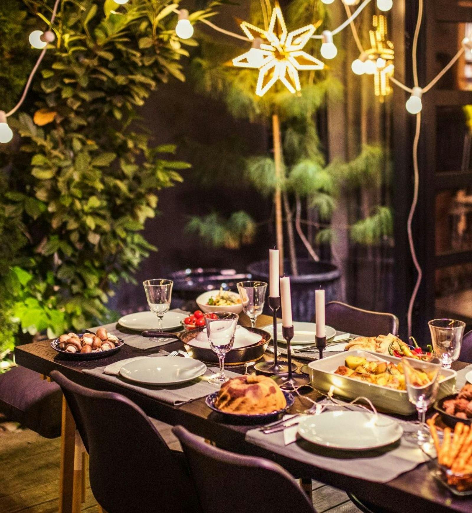 food, cutlery, glasses and candles on a timber outdoor table