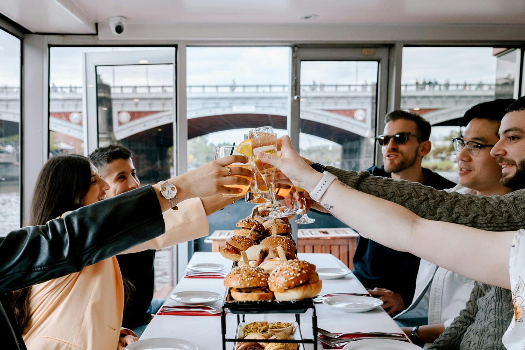 A group of friends having a cheers of their beverages aboard the cruise with brunch items.