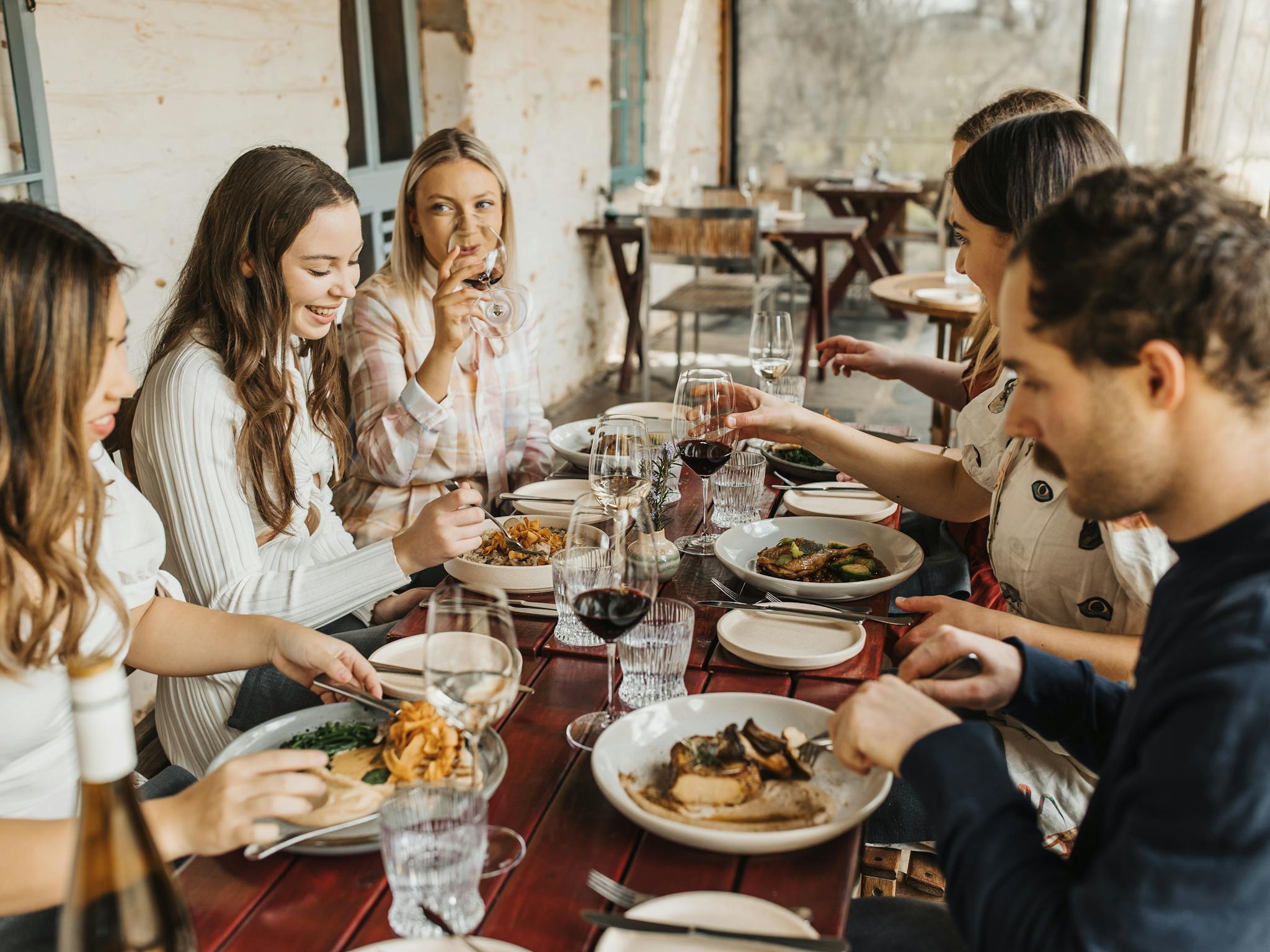 A group of people sharing a meal at a long table on the verandah at Skillogalee