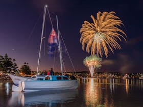 fireworks over a night sky with a small wooden boat