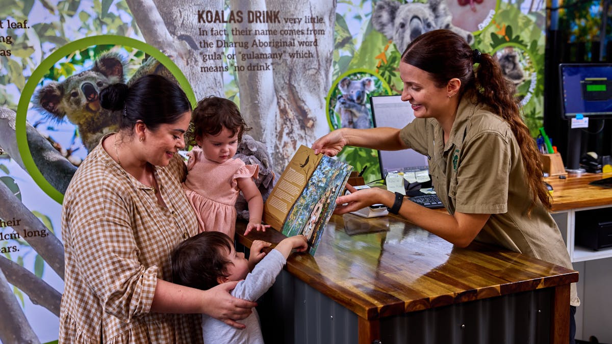 A wildlife keeper is presenting a family with a printed photo of their Koala Photo Experience.