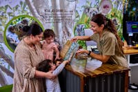 A wildlife keeper is presenting a family with a printed photo of their Koala Photo Experience.