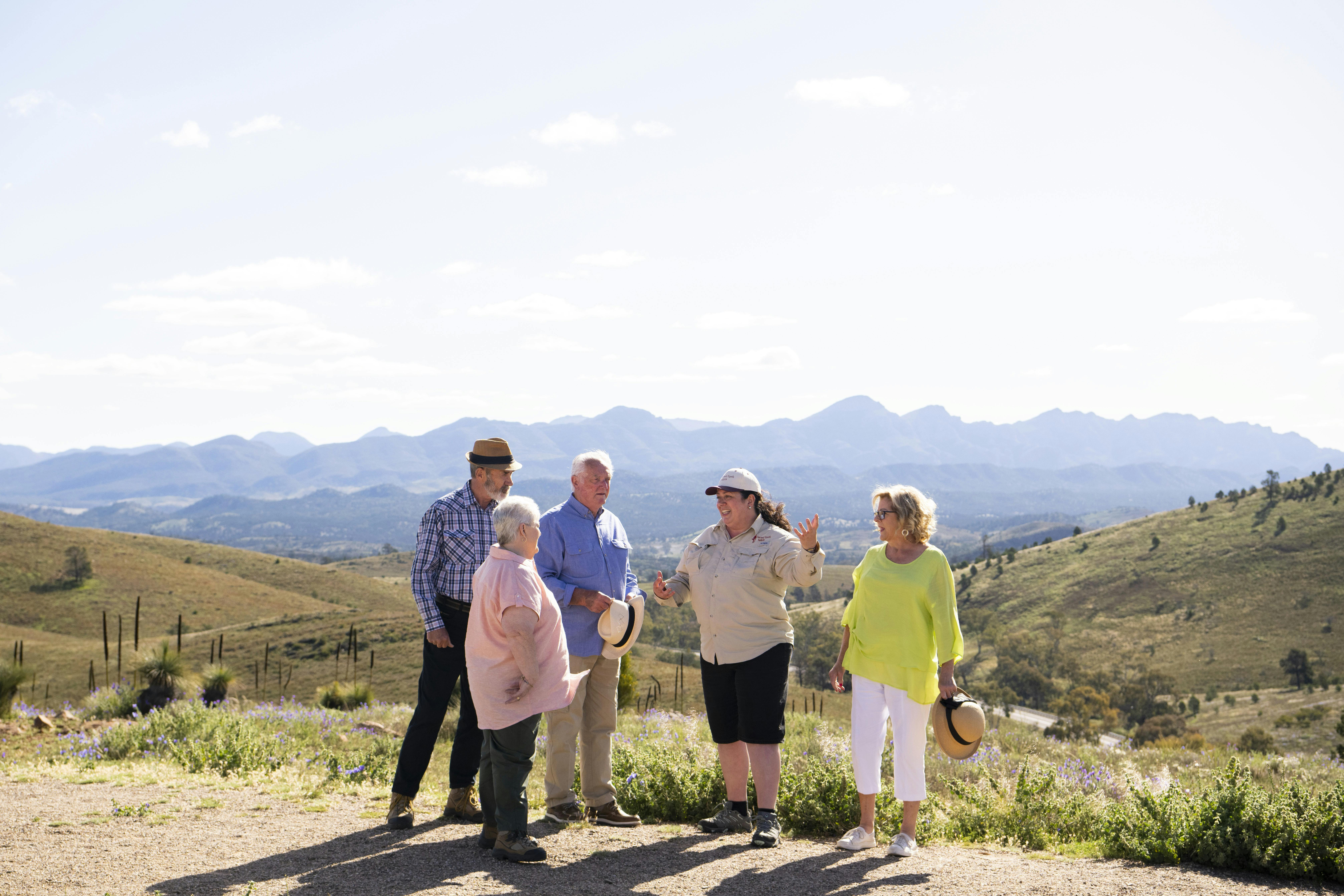 Tour guide talking to small group of people with mountains in the background