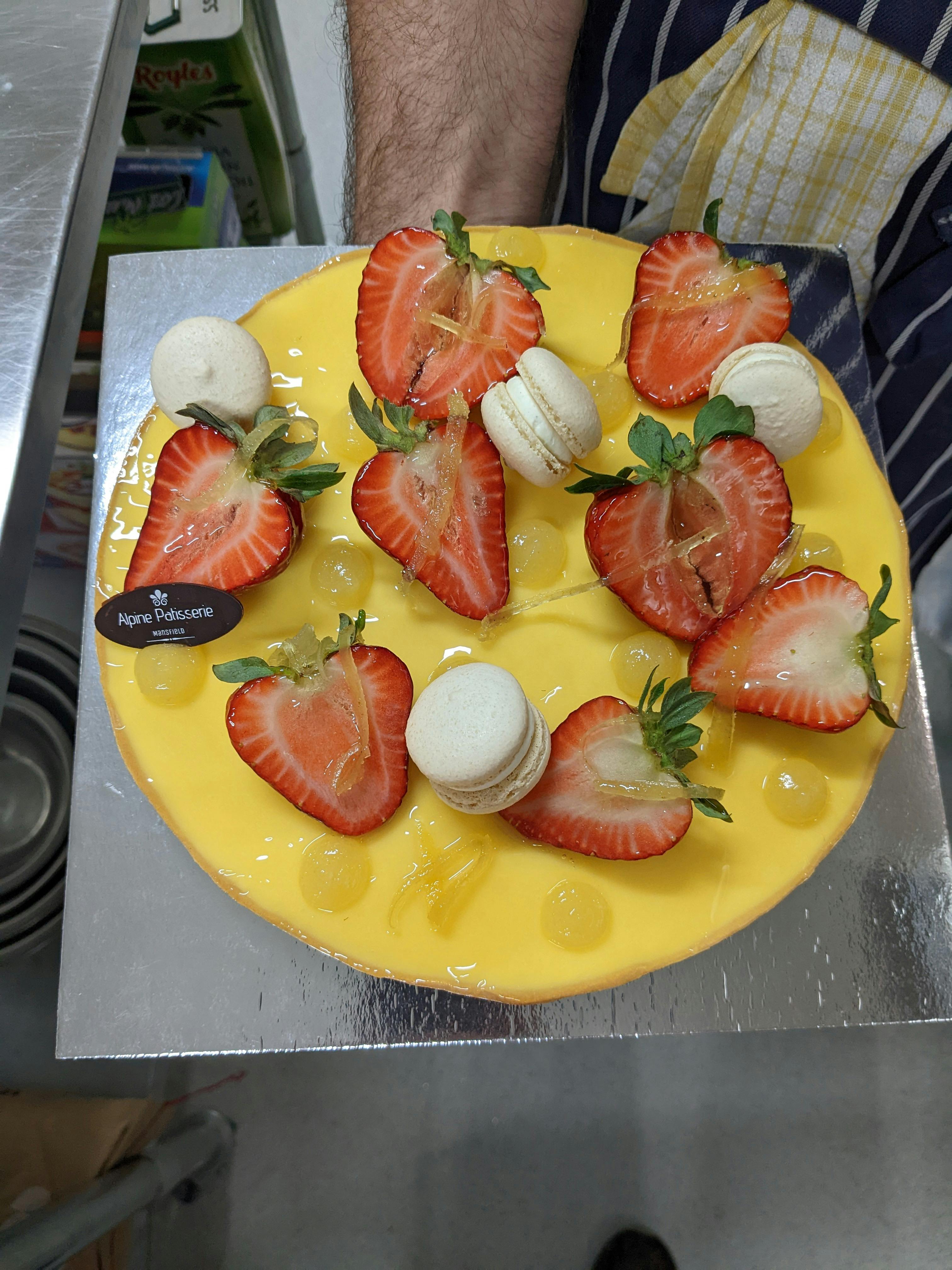 Zingy Lemon Brulle Tart topped with fresh strawberries and vanilla macarons