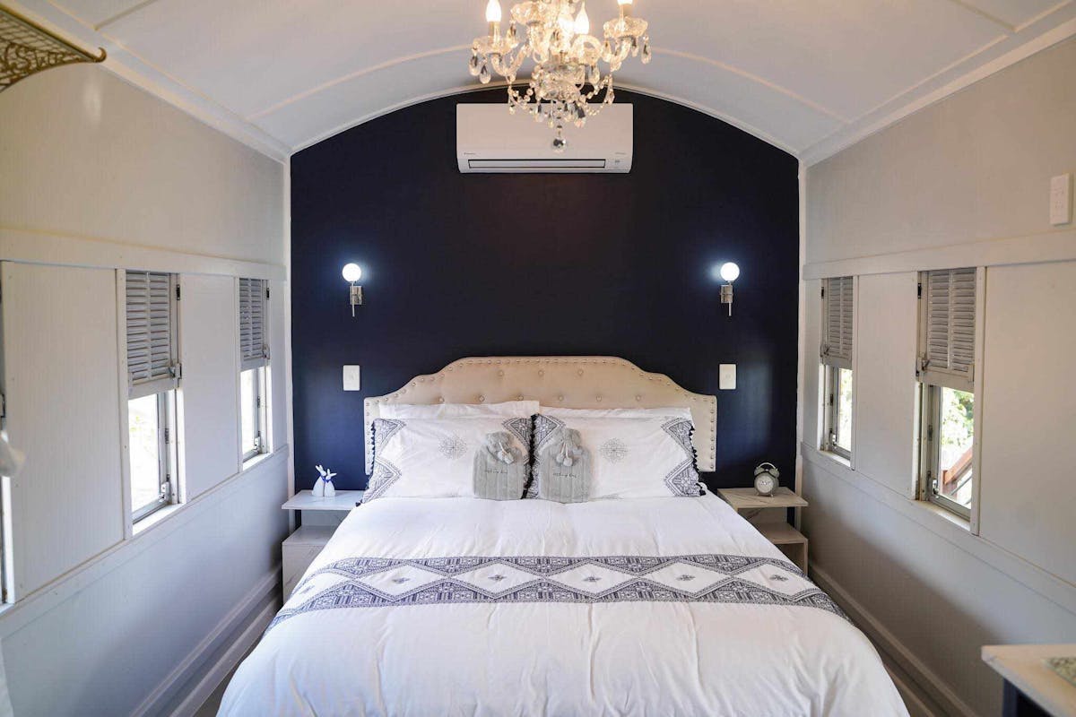 Elegant train carriage bedroom with a plush bed, chandelier, and vintage charm in a peaceful setting