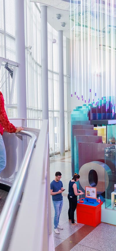 3 young people stand looking at a rainbow exhibit at Questacon