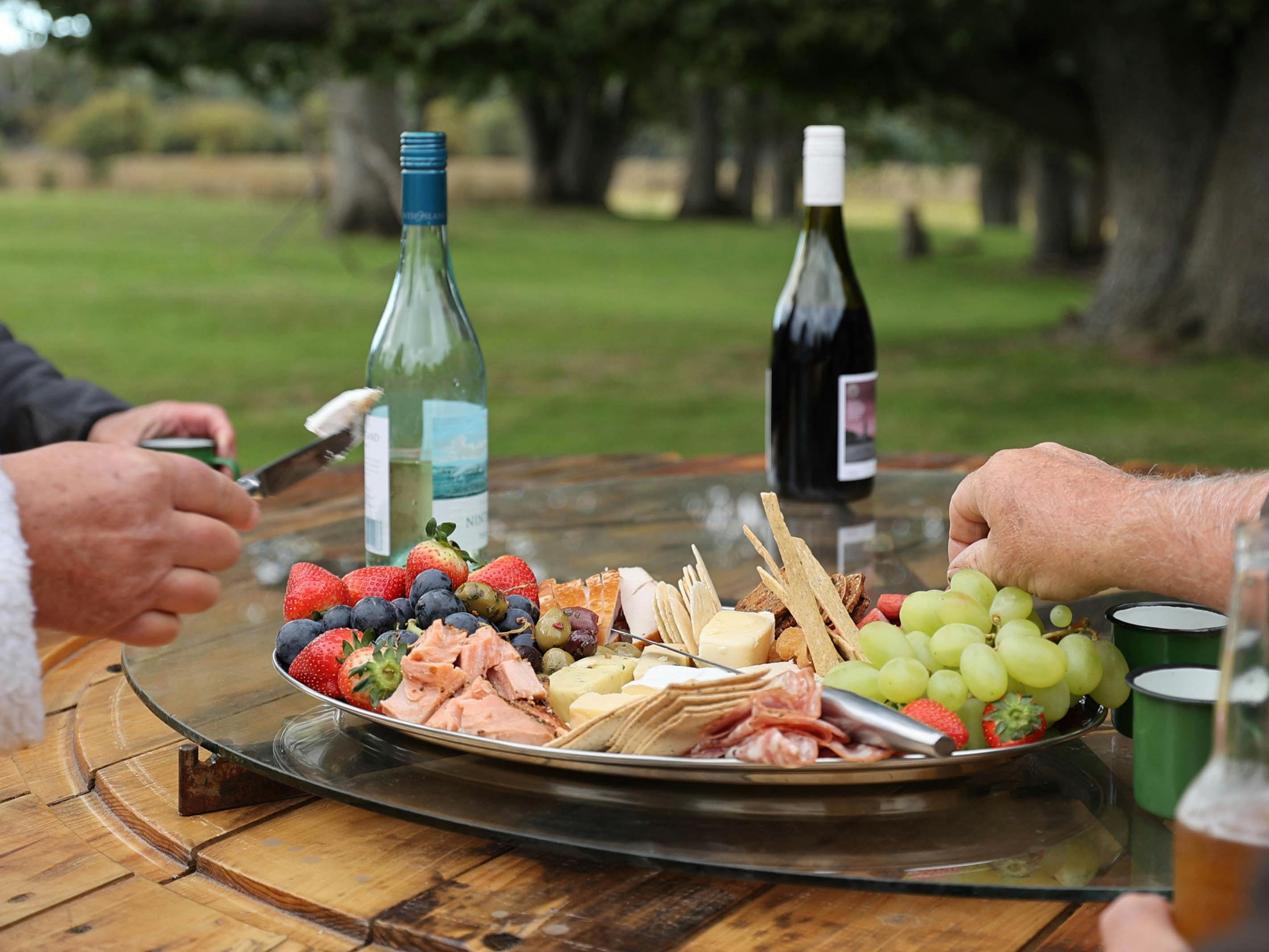 A platter of Tasmanian cheeses, smoked meats and fruit served outdoors