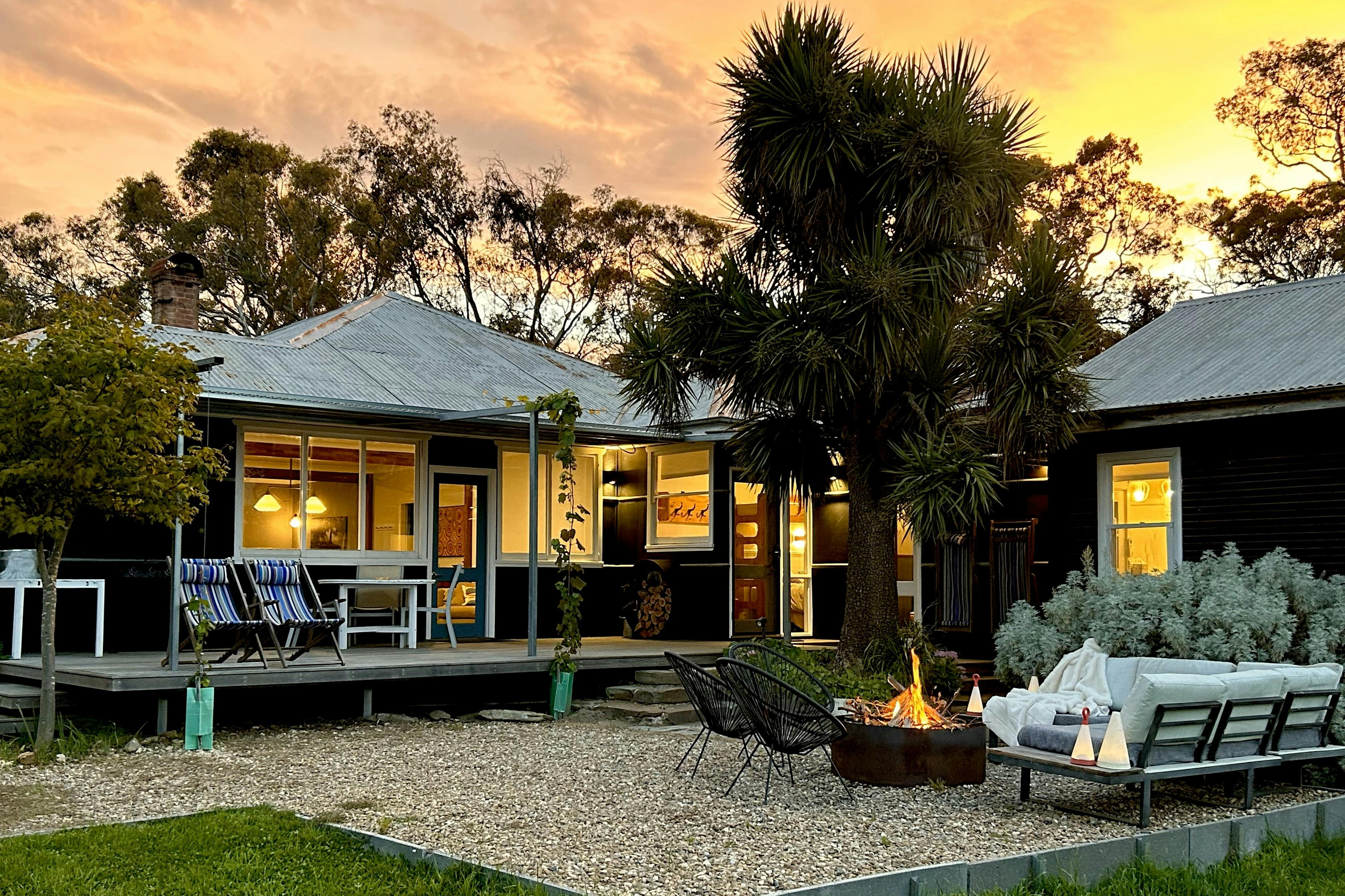 Black house at sunset with firepit in foreground.