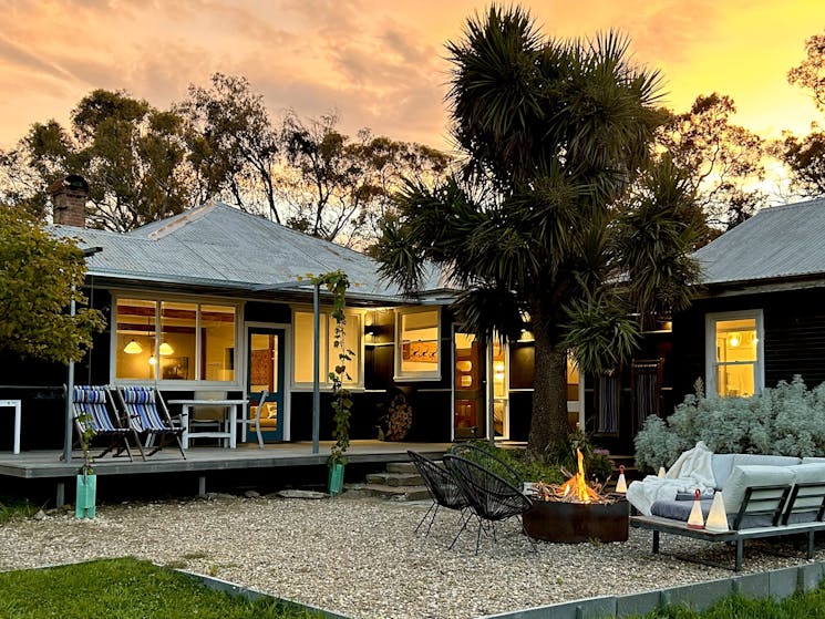 Black house at sunset with firepit in foreground.
