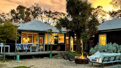 Black house at sunset with firepit in foreground.