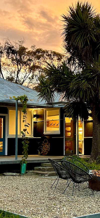 Black house at sunset with firepit in foreground.