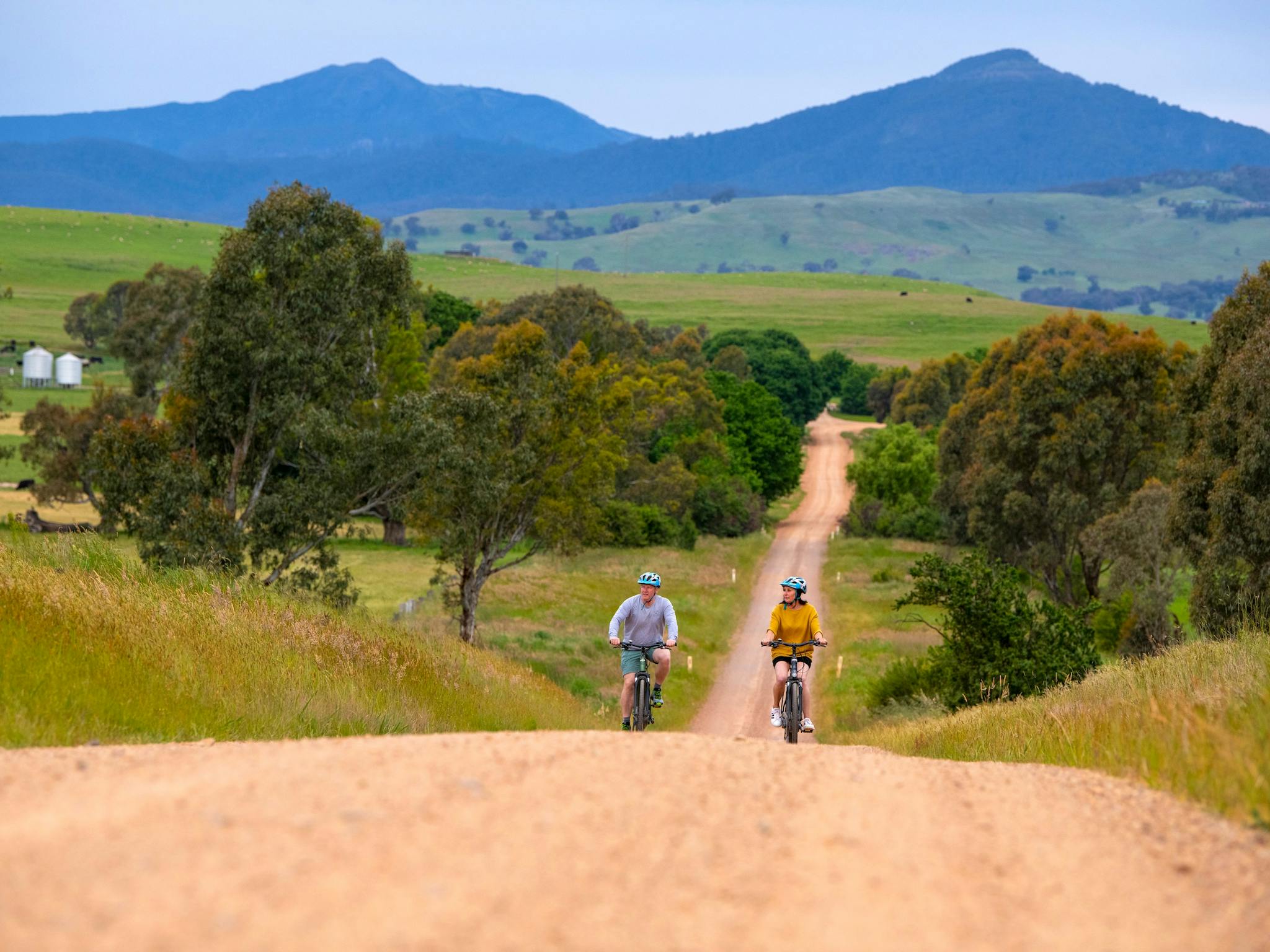 couple enjoying an ebike ride uphill with a mountain backdrop