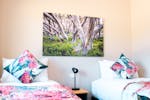 Two single twin beds with a wooden side table between them. Nature print on the wall