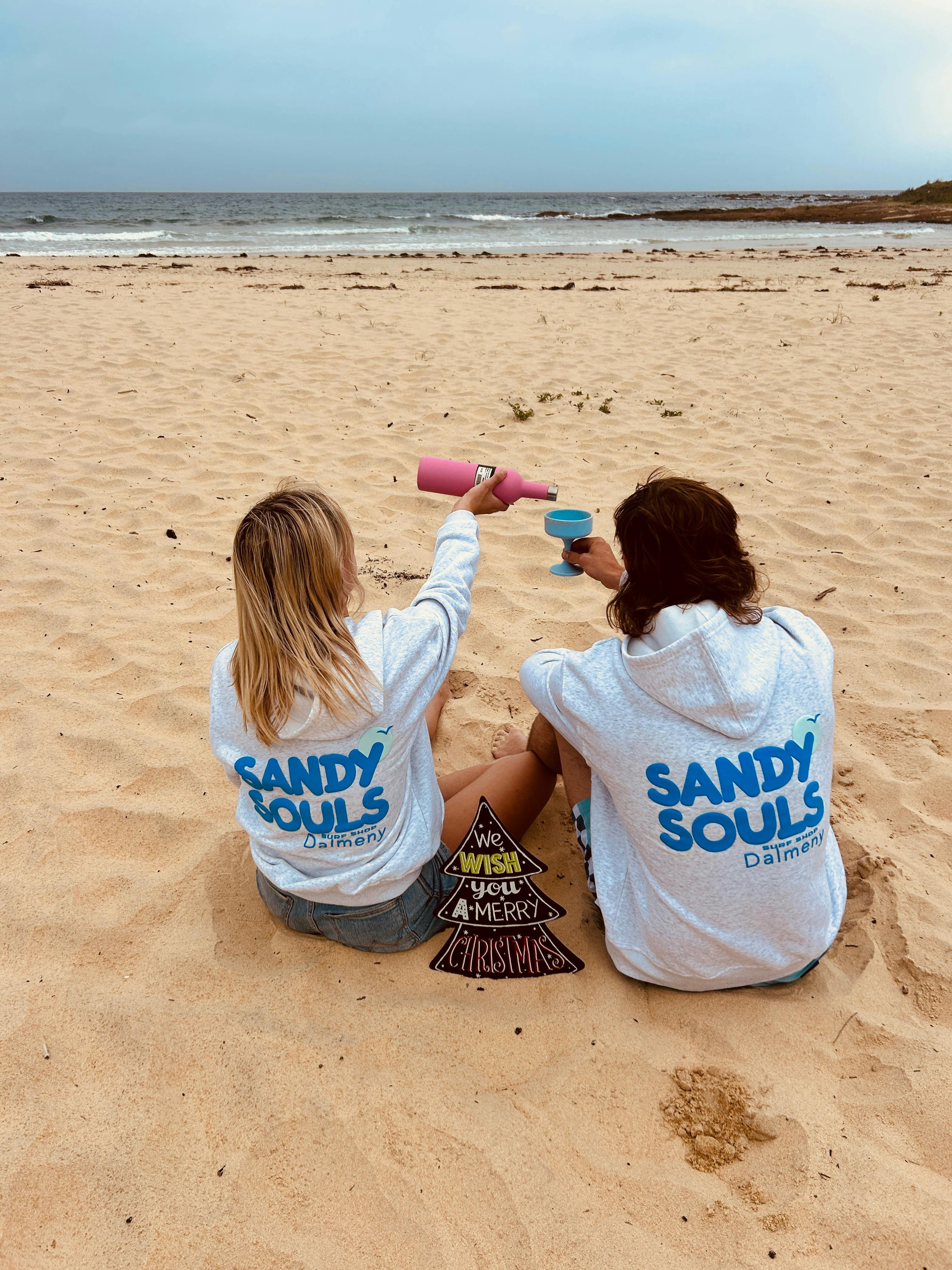 Two people wearing Sandy Souls Dalmeny hoodies on the beach in Dalmeny, NSW