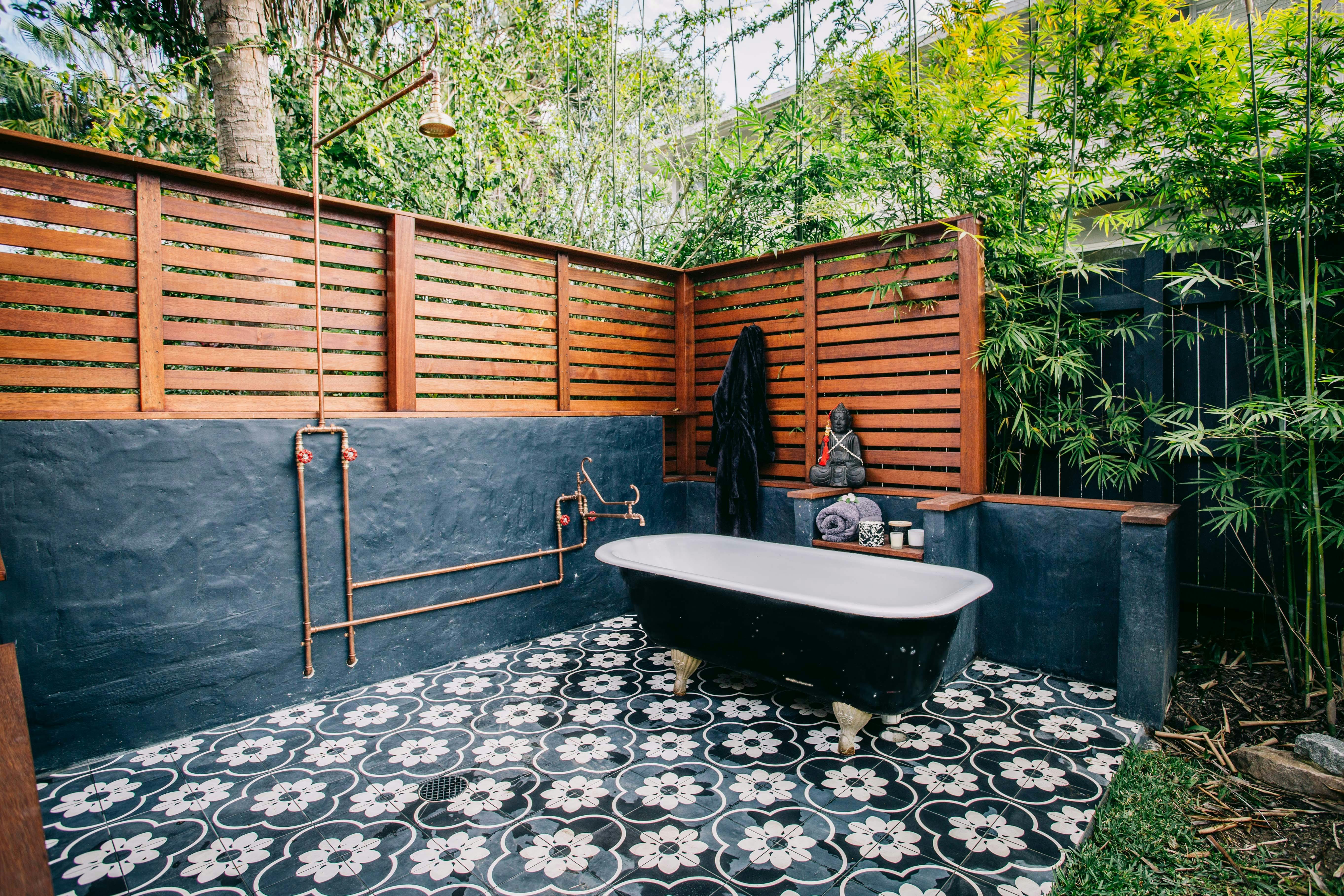 Outdoor bath and shower with brass taps and shower on a tiled floor at Bellingen Converted Church