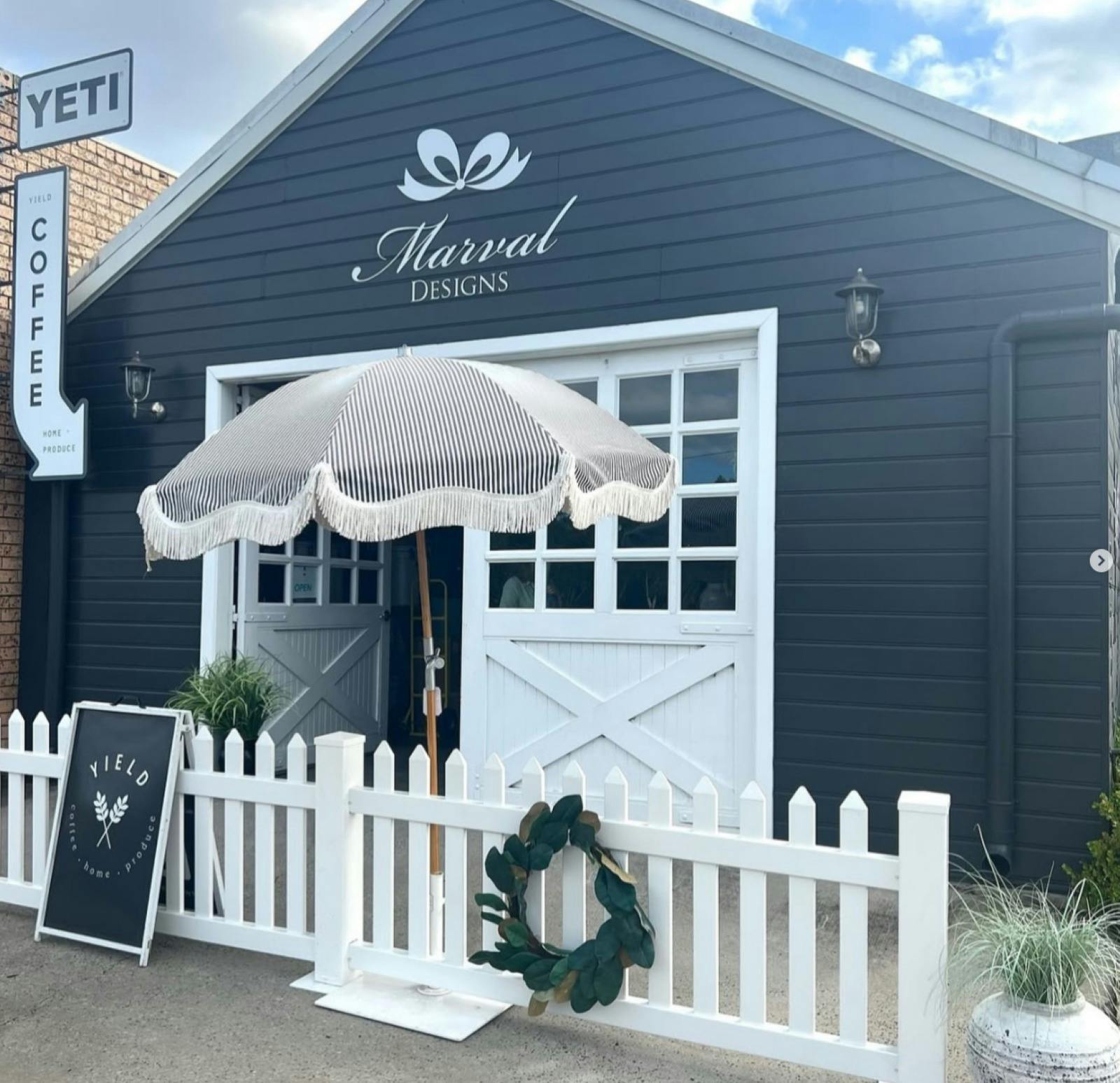 Yield Shop Front, white barn door entry with umbrella out the front