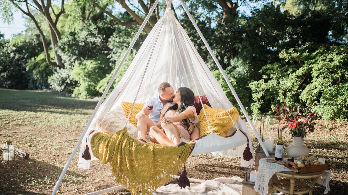 A couple enjoying a romantic picnic in a hanging tiipii pod at Soul Nook