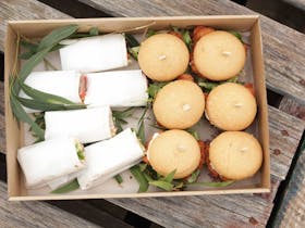 A platter box with sandwich wraps and burgers