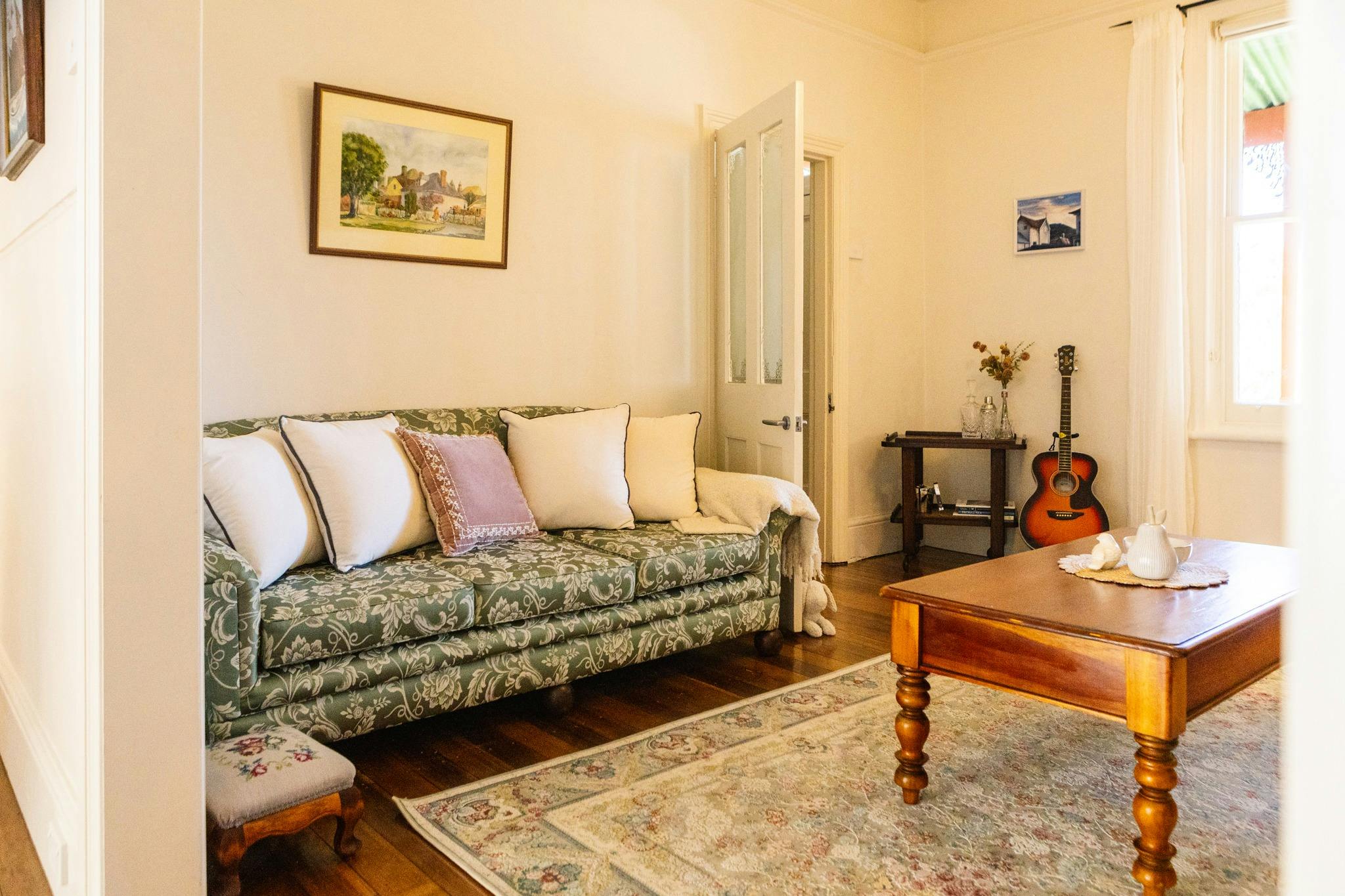 A cosy shot of the living room at Dukes on Quayle showing the couch, coffee table and guitar and drc