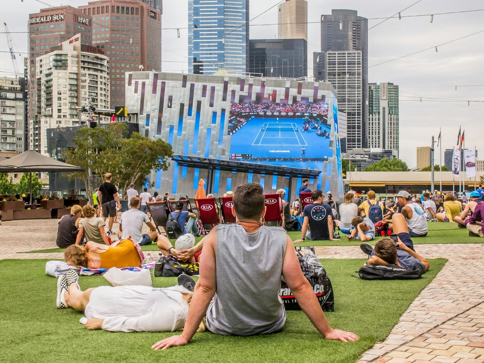 Visitors sit on the grass at Fed Square to enjoy the Australian Open on the Big Screen.