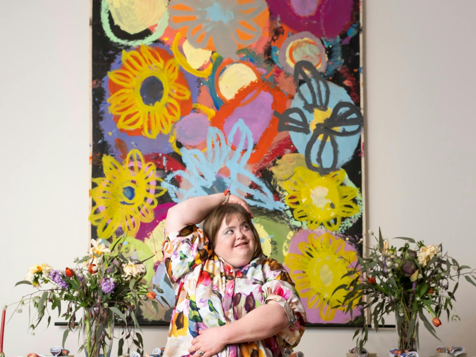 Artist Catherine McGuiness standing in front of bright, colourful artwork