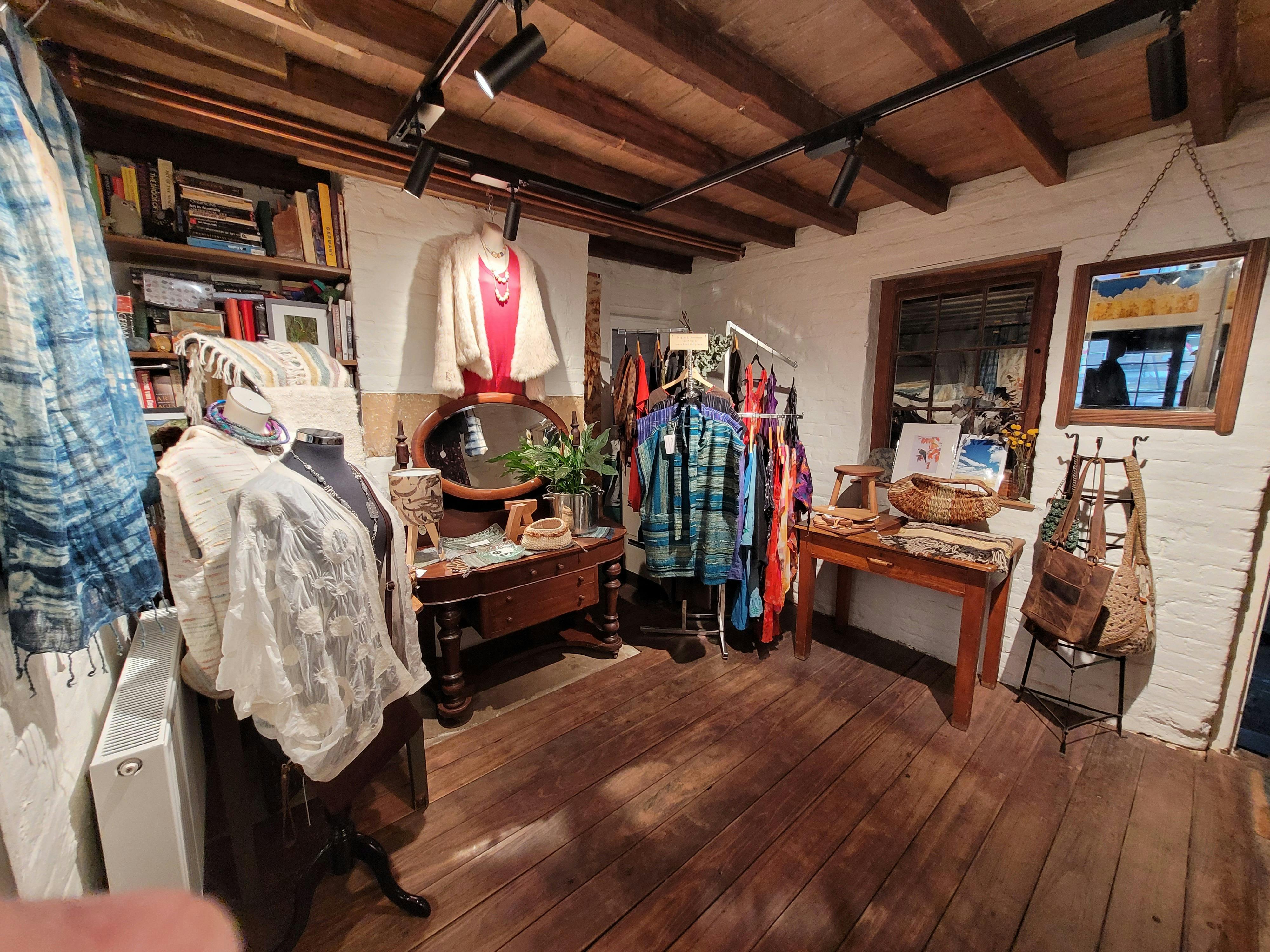 Timber floored room with clothing rack and display tables.