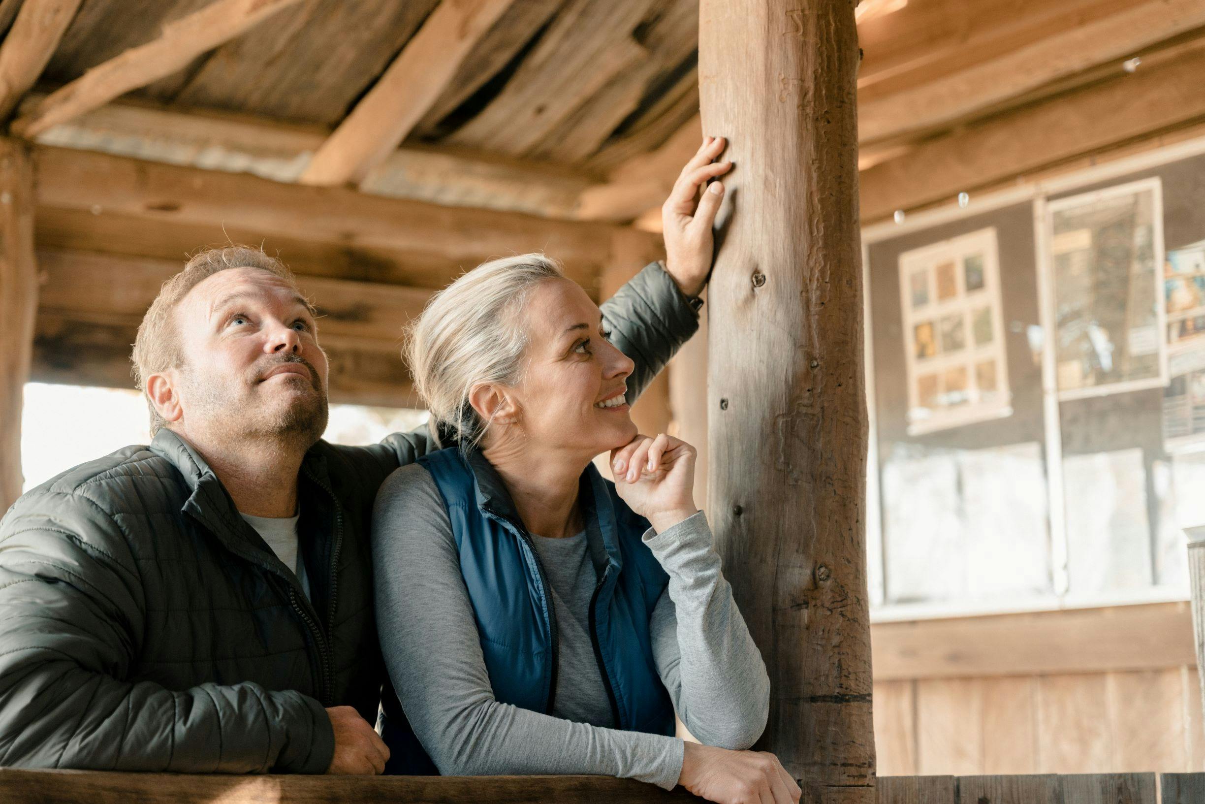 A closeup of a man and a woman standing inside a shearing shed, looking around.
