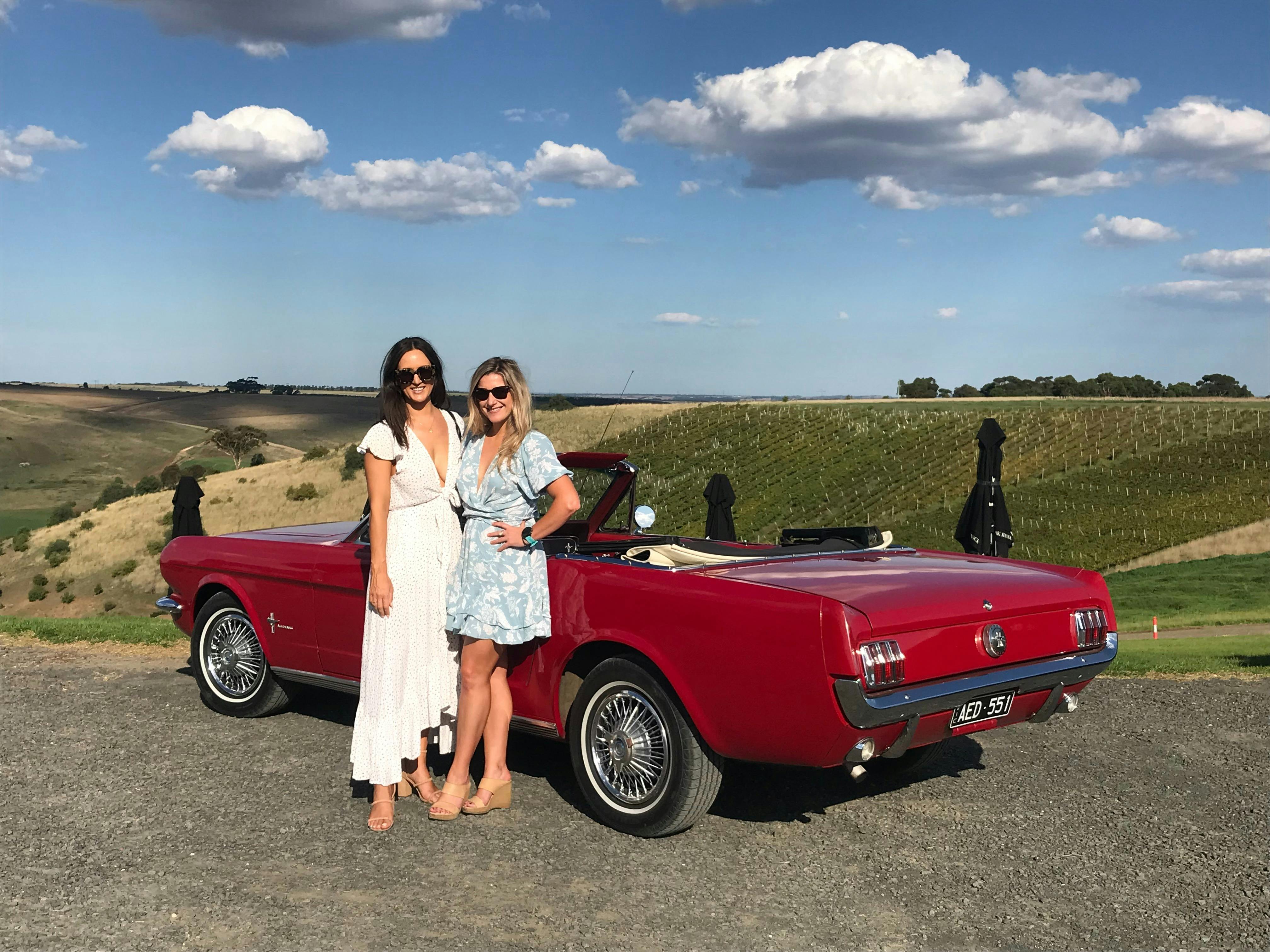 Two females on winery tour in a Vintage Mustang convertible