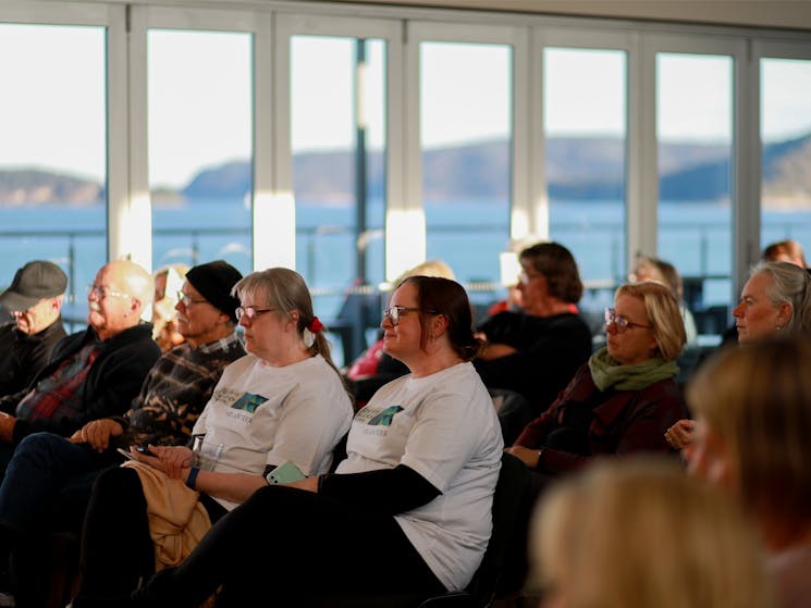 A crowd of Words on the Waves Writers Festival attendees sit in the venue, view of the coast outside