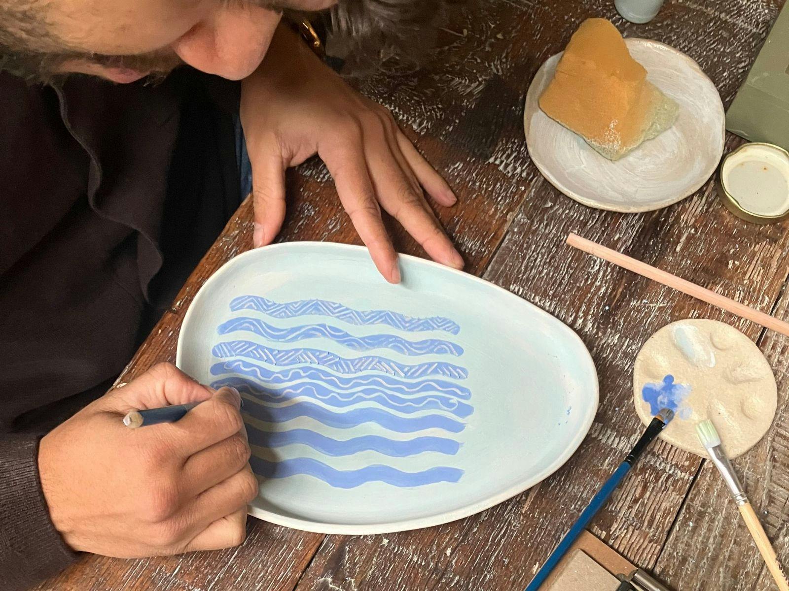 Male painting on a plate at a table