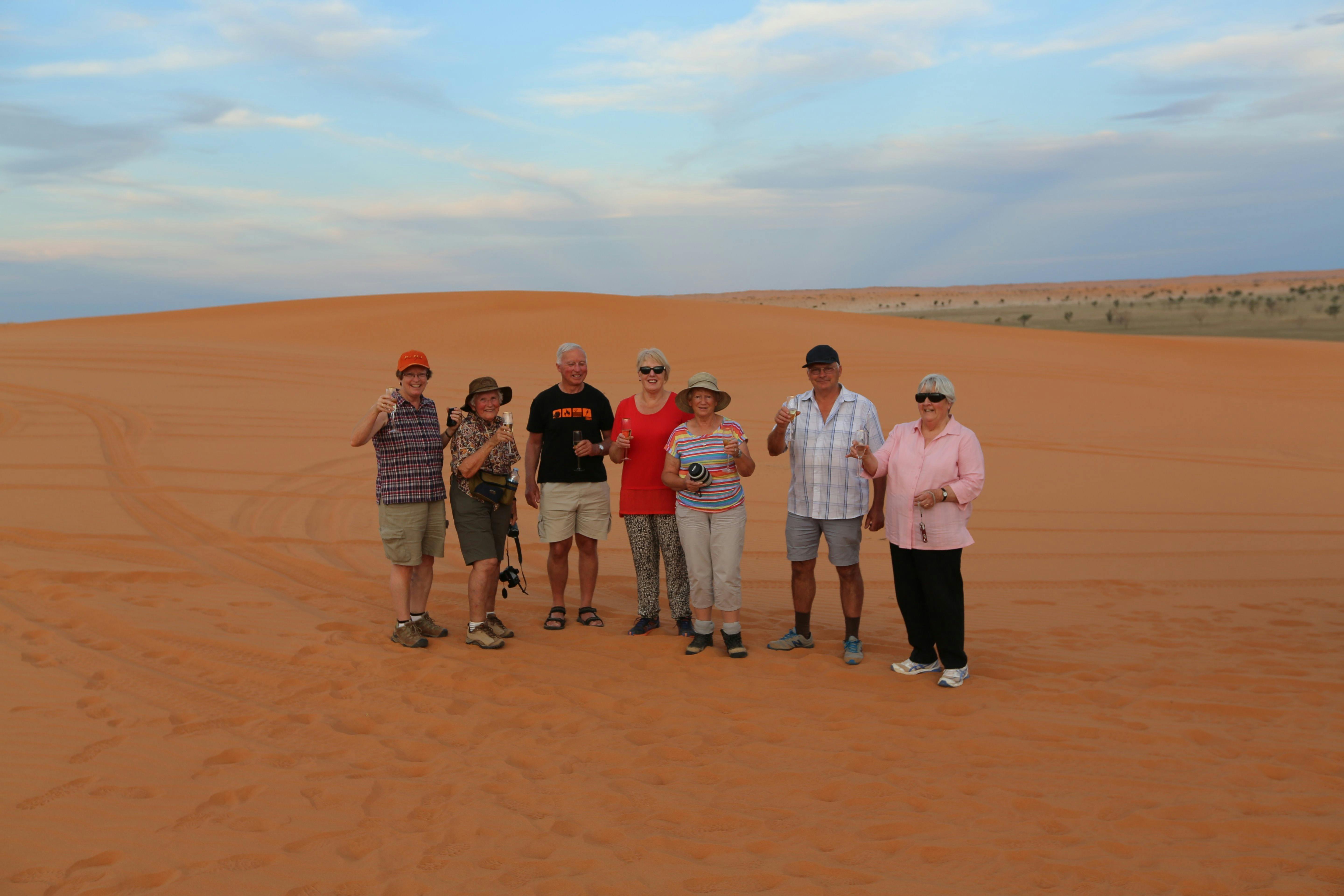 group of people having drinks on top of the Big Red sand dune