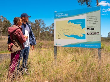 Couple looking at the Wivenhoe Hill Trails walking sign in Somerset